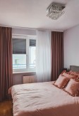 Szara roleta plisowana blackout (100% zaciemniająca) w ciepłej różowo-szarej sypialni